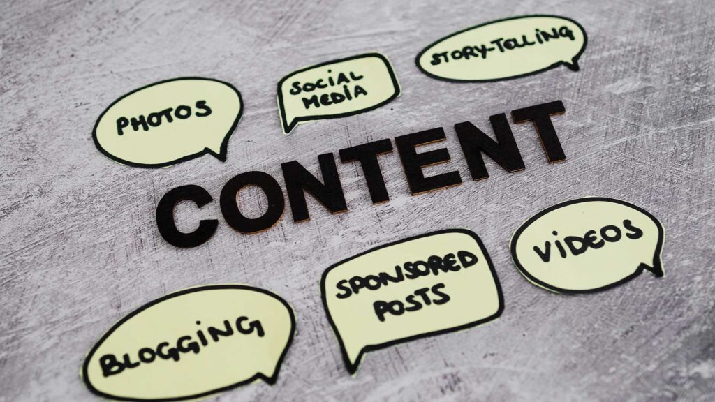 The image shows various content creation elements relevant to ecommerce, including photos, social media, storytelling, videos, blogging, and sponsored posts. The central focus is the word "CONTENT" in large letters, highlighting the importance of content creation for ecommerce businesses. The surrounding speech bubble icons represent different content formats and channels that can be leveraged for effective ecommerce content strategies. This image visually conveys the broad scope of "content creation for ecommerce" through the diverse set of content types and platforms depicted.